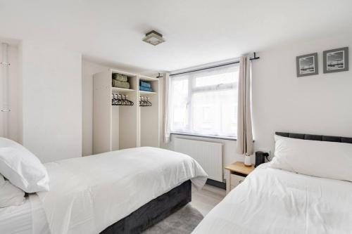 a white bedroom with two beds and a window at The Barack Nest Colchester in Colchester