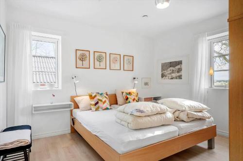 a bedroom with a bed with white walls and windows at 8119-Praesto-Over-Lyngen-19 in Præstø