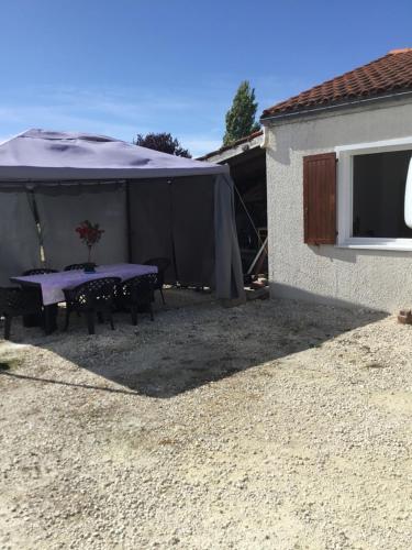 a table and chairs under a tent next to a building at Bienvenue dans notre maison in Saint-Georges-dʼOléron