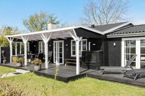 a black house with a porch and a deck at 8207-Vordingborg-Strandparken-22 in Vordingborg