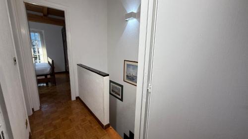 a hallway with a white wall with a light on it at Hostdomus - La Casa di Merlino in Oulx