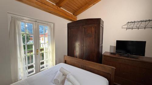 a bedroom with a bed and a dresser and a television at Hostdomus - La Casa di Merlino in Oulx