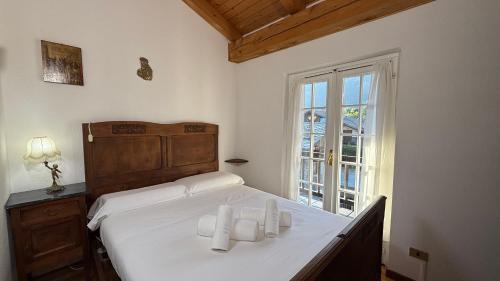 a bedroom with a bed with white sheets and a window at Hostdomus - La Casa di Merlino in Oulx