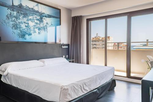 Un dormitorio con una cama y una ventana grande. en Bakour La Manga Splash, en La Manga del Mar Menor