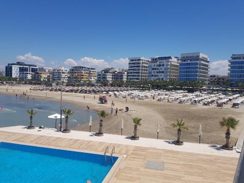 a view of a beach and a swimming pool with palm trees at Seaside Bliss in Qerret Beach in Golem
