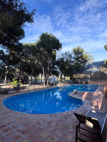 a swimming pool in a courtyard with trees and a building at Camping Moraira in Moraira