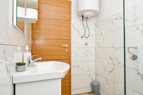 a white bathroom with a sink and a shower at Apartman Nina in Jajce
