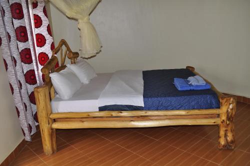 a small wooden bed with a blue blanket and pillows at Nyamunyonyi Lake Resort in Kabale