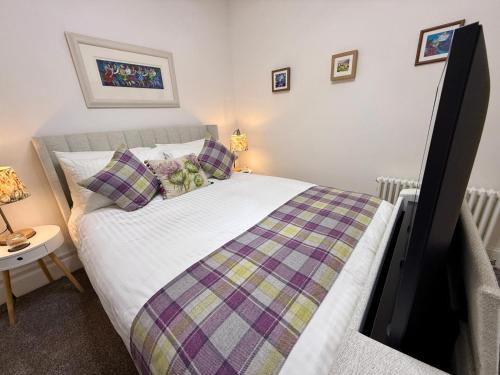 a bedroom with a bed with a checkered blanket at Carron Cottage in Inverness