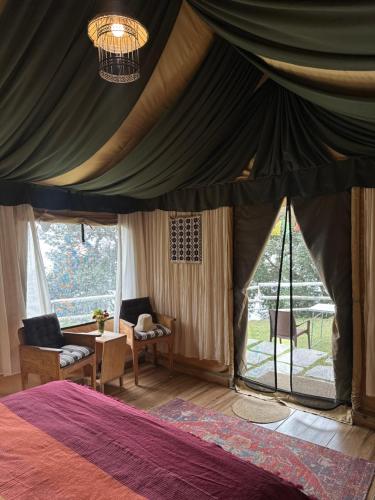 a bedroom with a tent with a bed and a table at Jaadooghar x Dug Dug Camps, Bhimtal in Bhīm Tāl