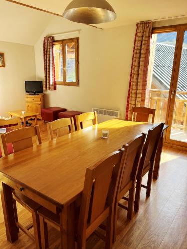 une salle à manger avec une grande table et des chaises en bois dans l'établissement VVF Résidence Albiez-Montrond Maurienne, à Albiez-Montrond