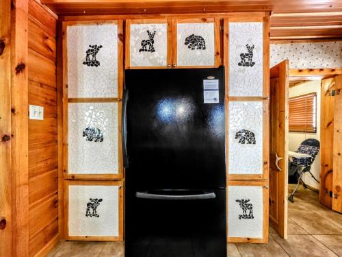 a black refrigerator in a room with wooden walls at The Skinners Cabin Hot Tub Fireplace Grill in Townsend