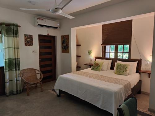 a bedroom with a bed and a chair and a window at Villa Lyvie ayurvedic hotel in Tangalle