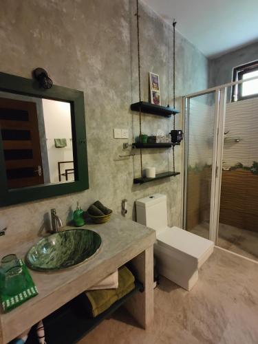 a bathroom with a sink and a toilet and a mirror at Villa Lyvie ayurvedic hotel in Tangalle