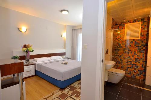 a bedroom with a bed and a bathroom with a toilet at Calis Hotel in Cesme