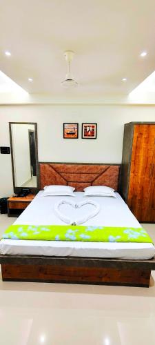 a bedroom with a large bed with a wooden headboard at Manyavar Guest House Rooms & Family Service Flats in Deoghar