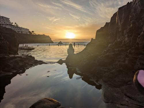 a person sitting on the beach watching the sunset at w DiscoveryCanarias II in San Miguel de Abona