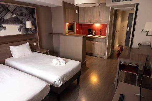 a hotel room with two beds and a kitchen at B&B HOME Caen Centre Gare in Caen