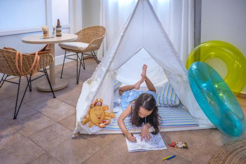 a little girl laying in a teepee in a play tent at SERHS Experience Suítes in Natal