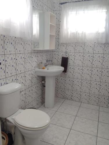 a white bathroom with a toilet and a sink at Roche Kerlan Apartments in Anse Kerlan