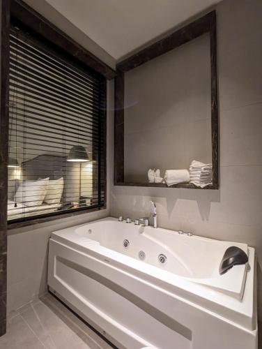 a white bath tub in a bathroom with a mirror at The LC Hotel in Lahore