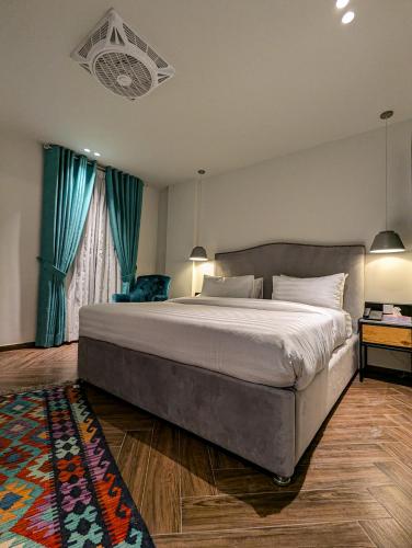 a bedroom with a large bed with blue curtains at The LC Hotel in Lahore