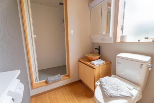 a bathroom with a toilet and a sink and a mirror at Serenity & Solitude Chalets, walk to the lifts Happoone Ski Resort in Hakuba