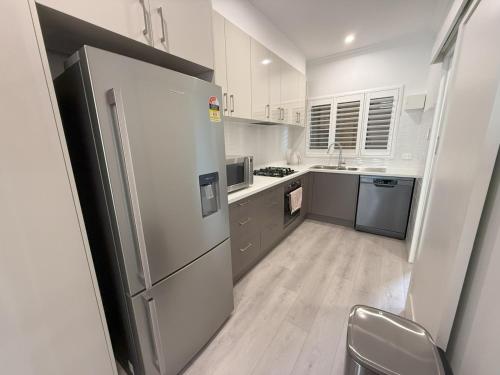 a white kitchen with a refrigerator and a sink at Happy BNB at Beach side semaphore park in Port Adelaide