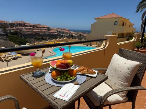 a table with a bowl of fruit and drinks on a balcony at Sunny Apartment Loma de Arguineguín in Arguineguín