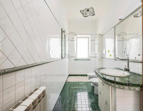 a white bathroom with two toilets and a sink at Casa di Clara Fregene in Fregene