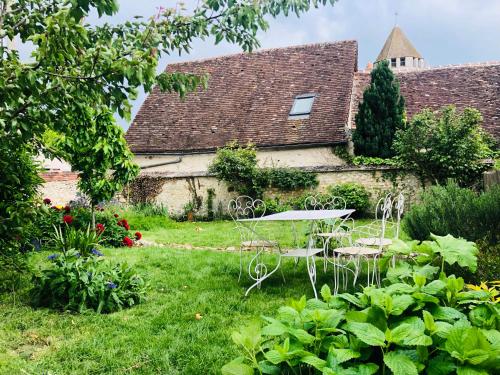 ogród ze stołem i krzesłami przed budynkiem w obiekcie Maison d'hôtes L'ormerie- Au coeur de la ville médiévale w mieście Provins