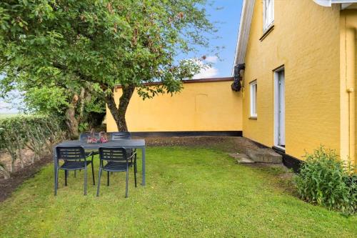 a table with chairs in front of a yellow house at 4015-Stege-Sondre-Landevej-19 in Stege