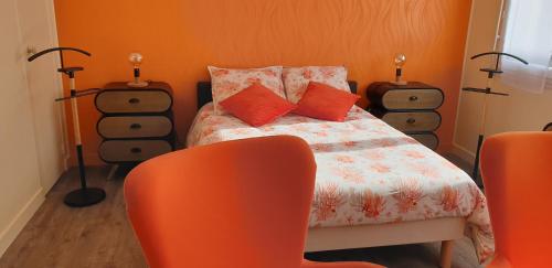a bedroom with a bed with orange walls and orange chairs at A 2 pas des iles à Concarneau in Concarneau
