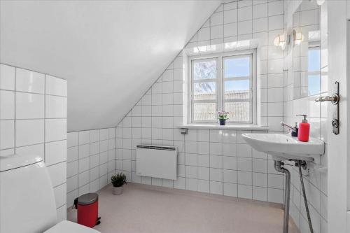 a white tiled bathroom with a sink and a window at 7017-Bogo-By-Fruekildevej-17 in Bogø By