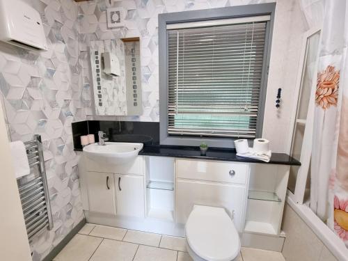 a white bathroom with a toilet and a sink at Oak Lodge 10 Hot Tub in York