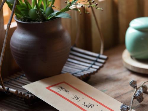 a table with a vase and a card with a plant at Dan’s Sea Guest House Hangzhou in Hangzhou