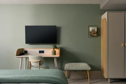 1 dormitorio con TV y escritorio con silla en Van der Valk Hotel Volendam - Recently renovated, en Volendam