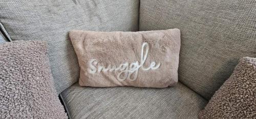 a pillow with the word snoopy on a couch at Refurbished 4-Bed Home Near Hospital & Station in Chatham