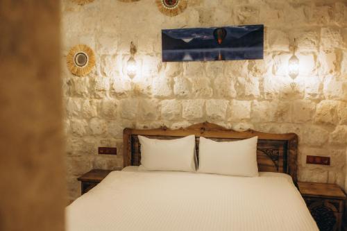 a bed with white pillows in a room with a stone wall at Timur inn Cappadocia in Goreme