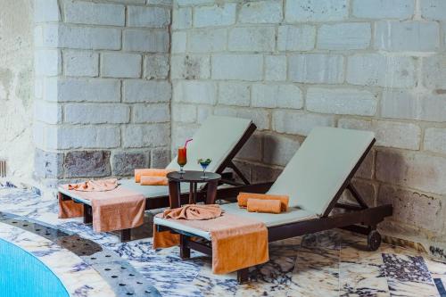 two lounge chairs and a table in front of a wall at Utopia Cave Cappadocia in Urgup