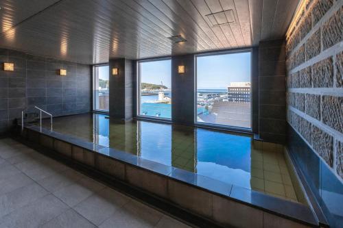 a swimming pool in a building with a view of the ocean at Hotel Sonia Otaru in Otaru