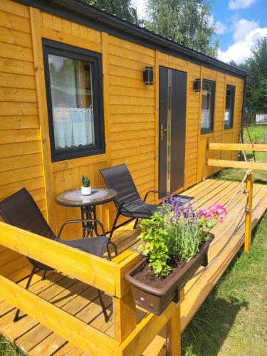 a cabin with a deck with two chairs and a table at Leśnisko in Niegowa