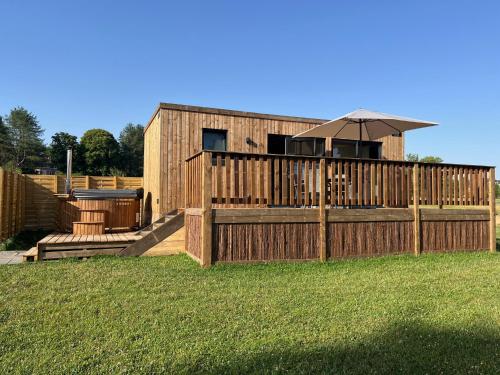 a wooden fence with an umbrella in a yard at Gîte avec son SPA privatif in Le Nouvion-en-Thiérache