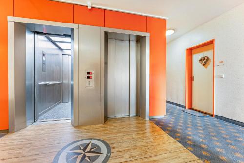 an empty corridor of an office with orange walls at Ferienwohnung 'Segelyachten-Perle' in Strande