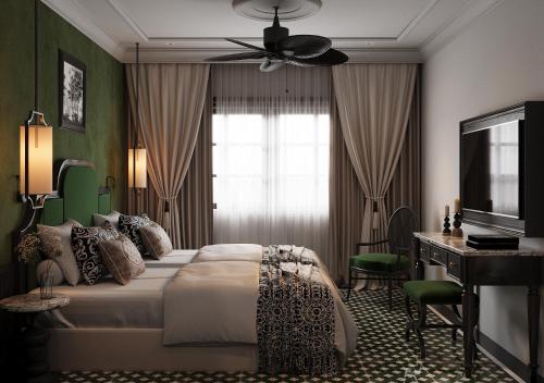 a bedroom with a bed and a desk and a window at L'Heritage Riverside Hoi An in Hoi An