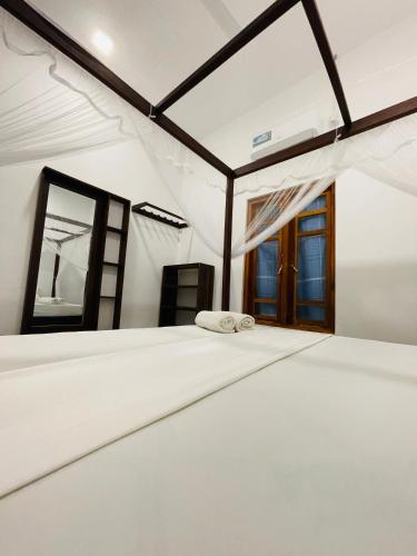 a white bed in a room with windows at 2nd Home Villa in Pottuvil