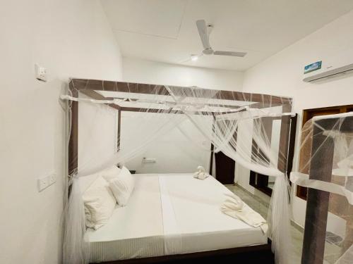 a white bed with a canopy in a room at 2nd Home Villa in Pottuvil
