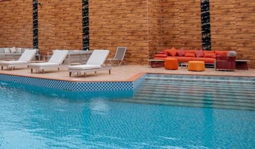 a swimming pool with lounge chairs and a couch at Swiss International Rancho Valeria, Warri in Warri