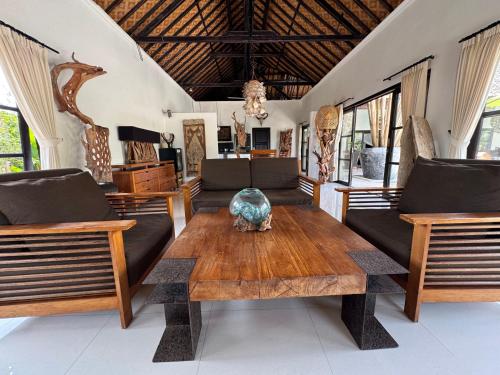 a living room with a wooden table and chairs at Beautiful Beach Villa Nujum with staff. in Lovina