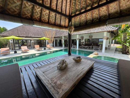 a wooden table sitting in front of a swimming pool at Beautiful Beach Villa Nujum with staff. in Lovina